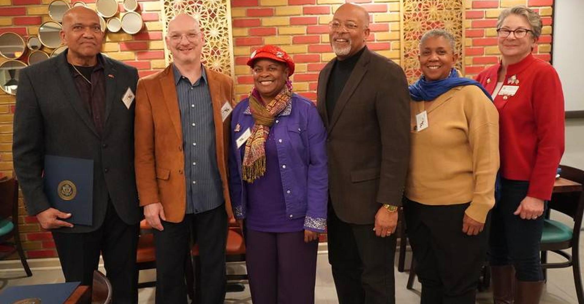 A man in a suit standing with men and women for a photo.