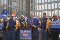 A group of men lined up behind a lectern at a rally. 